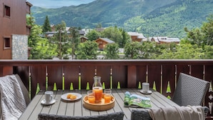 A wooden deck with a table set for breakfast, overlooking a mountainous landscape. - Résidence Pierre & Vacances Premium Les Fermes de Méribel (Les Allues)