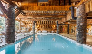 Ein Innenpool mit Steinsäulen, Holzbalken und Blick auf die Umgebung.
