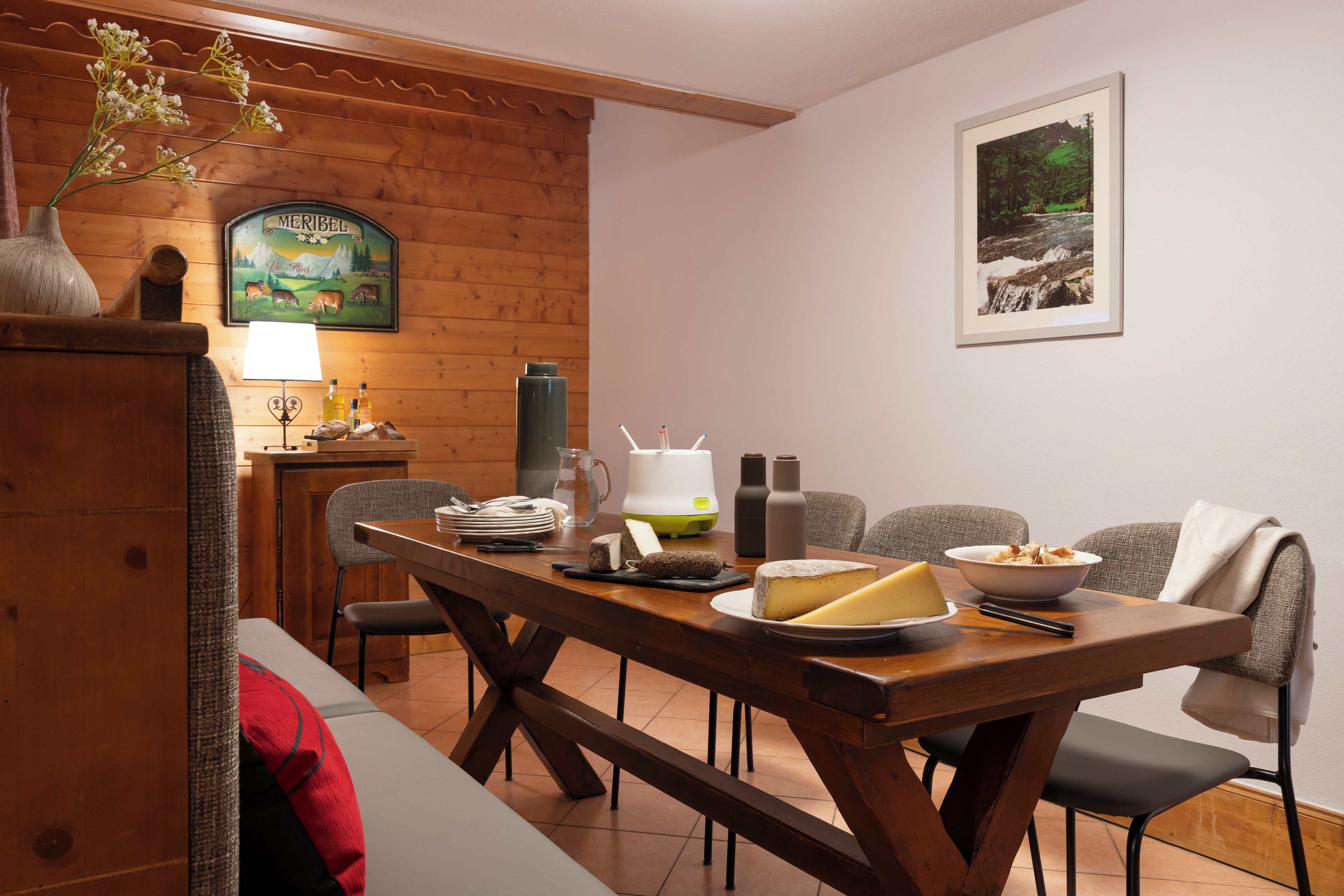 Ein Essbereich mit einem Holztisch, der für eine Mahlzeit gedeckt ist, einem gerahmten Bild an der Wand und einem Holzschrank mit einer Vase.