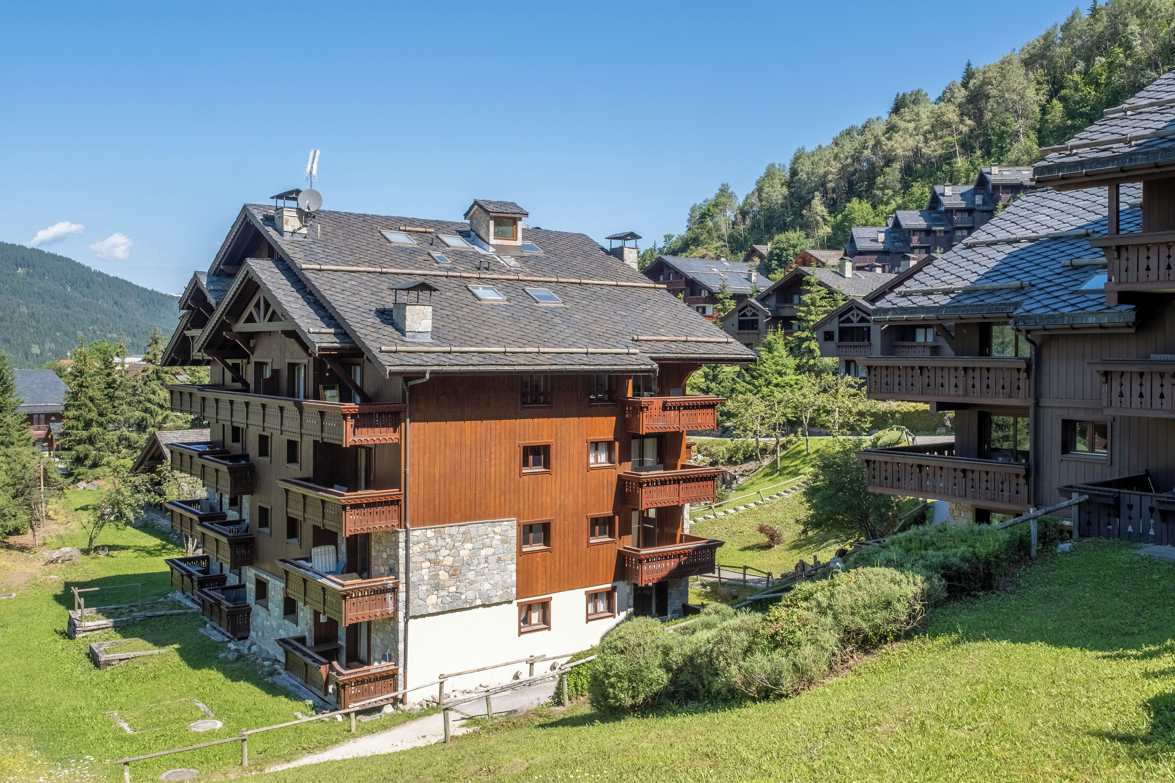 Un hotel de varios pisos con balcones, ubicado en una zona montañosa con abundante vegetación.