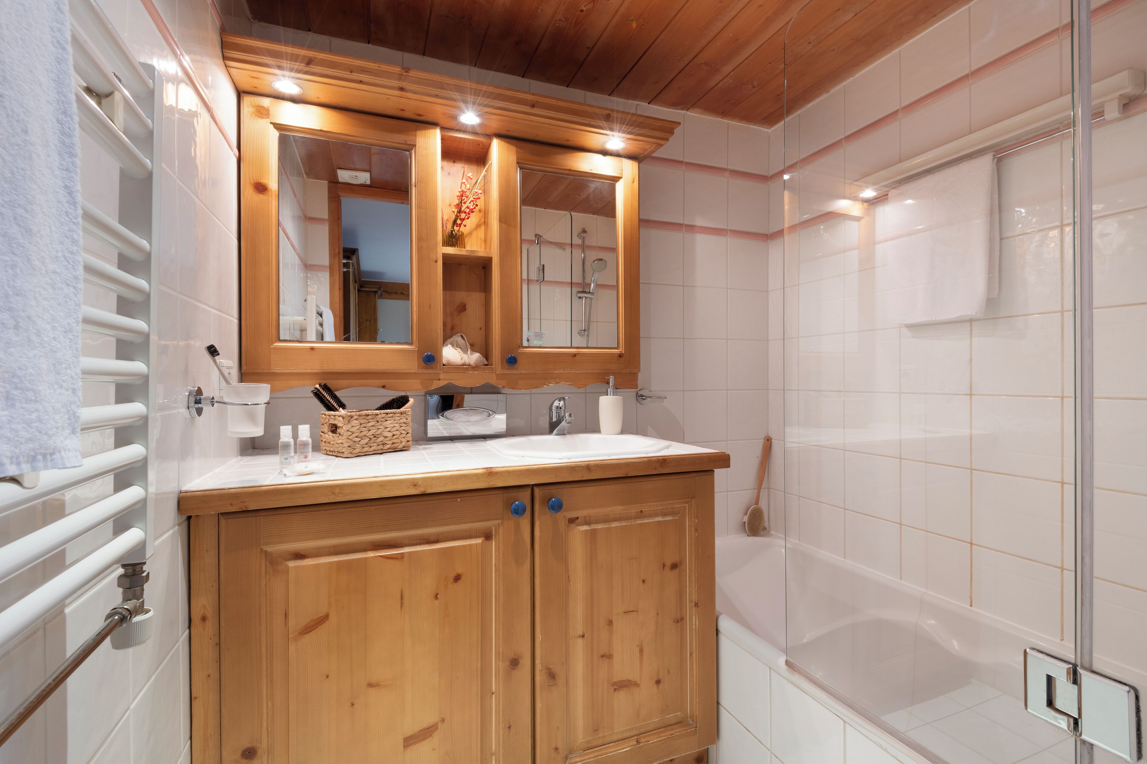 A bathroom with a wooden vanity, a mirror, and a shower area.