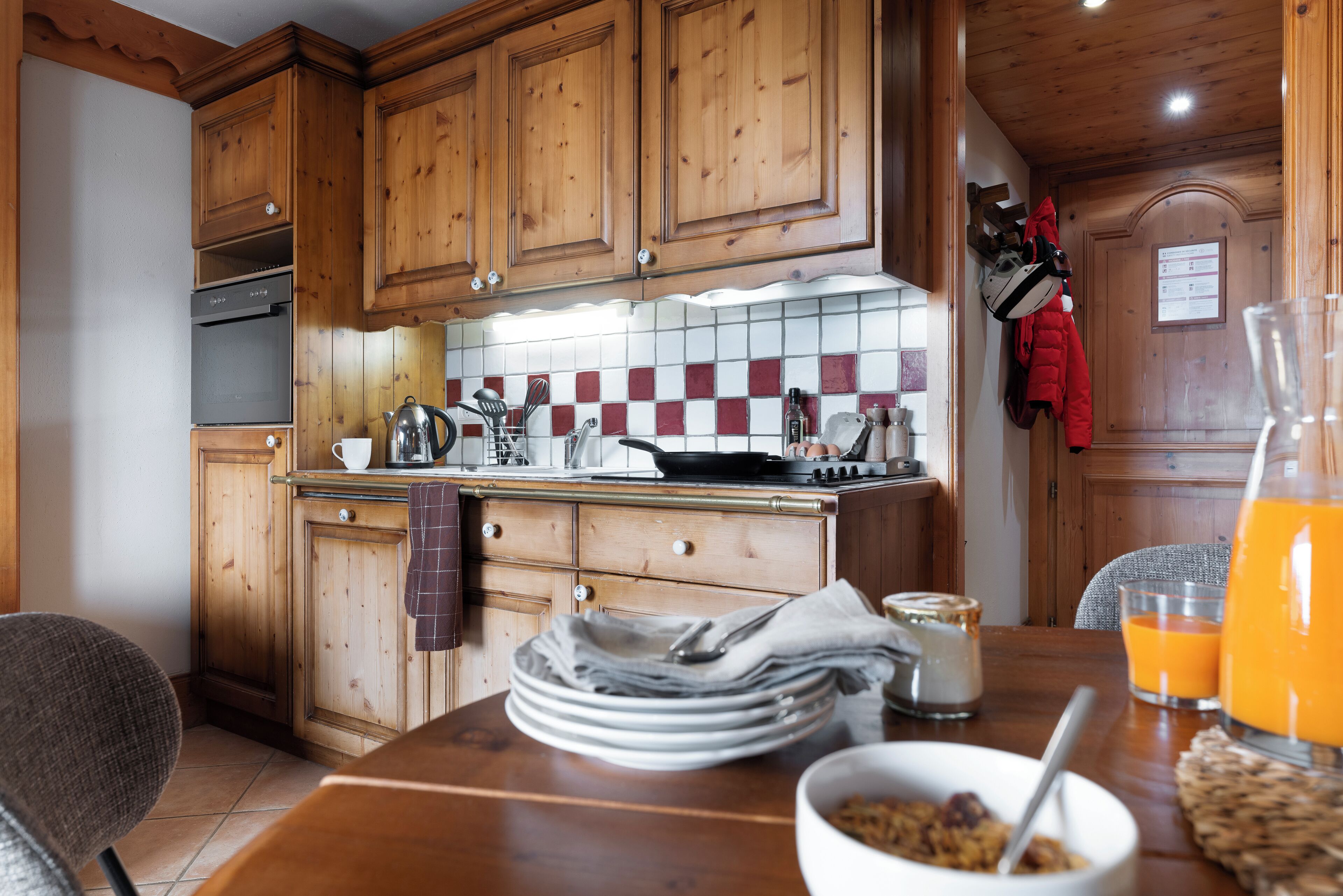 Una cocina con armarios de madera, salpicadero de azulejos y una mesa de comedor con cosas para el desayuno.