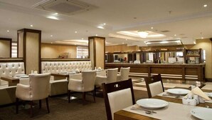 A hotel dining area with a buffet setup, cushioned seating, and a modern interior design. - Turist Hotel (Ankara)
