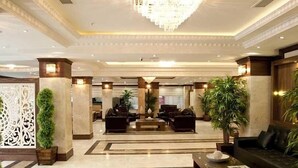 A spacious lobby with a central seating area, a chandelier, and decorative plants. - Turist Hotel (Ankara)