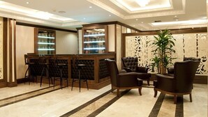 A lobby with a bar area, leather chairs, and a decorative wall. - Turist Hotel (Ankara)