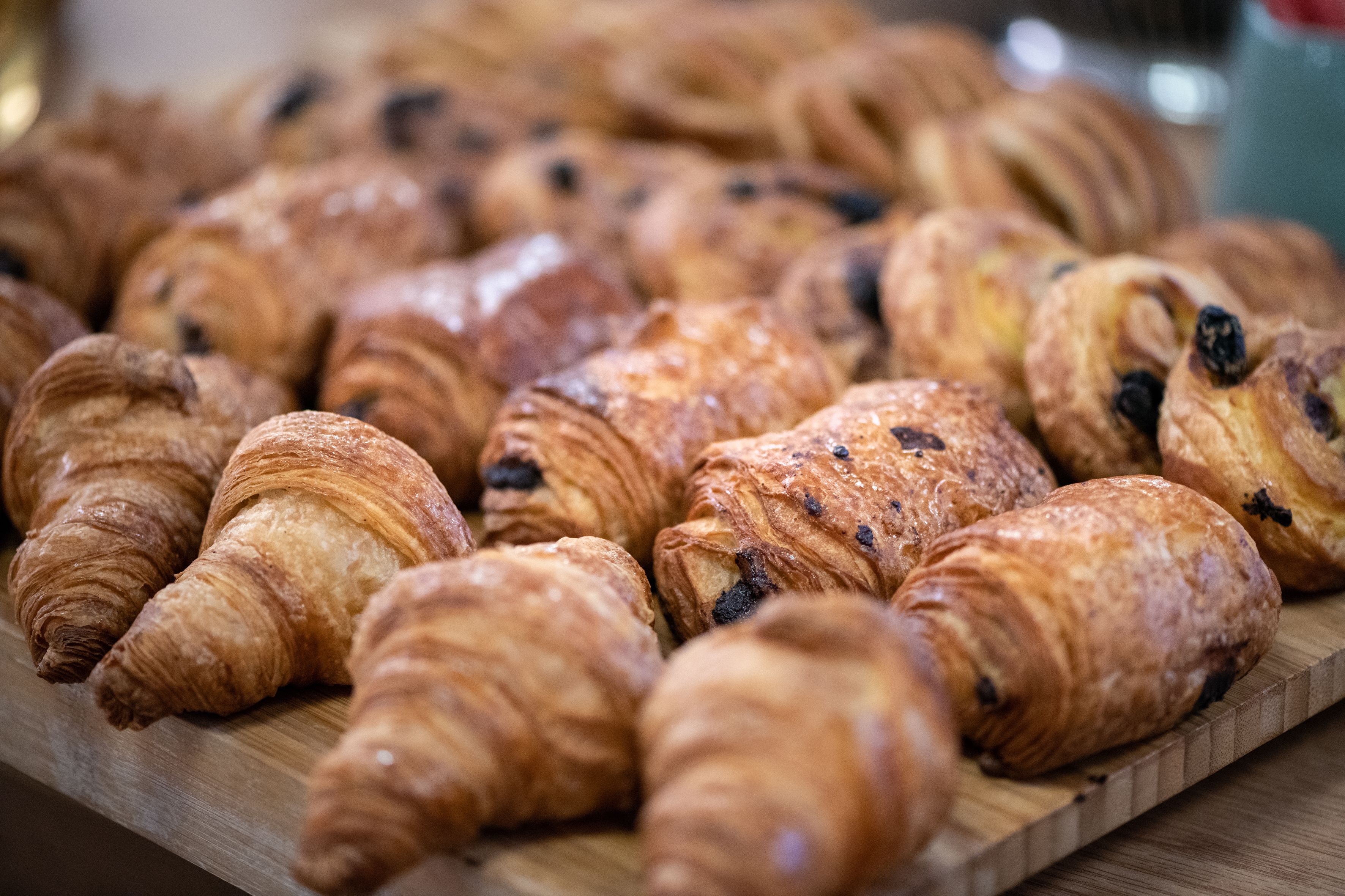 Puinen tarjoilulauta, jonka päällä on useita croissant-leivoksia.