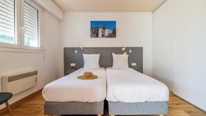 A double bed with grey bedding and a woven hat on the left side. - CERISE Dax - Les Jardins du Lac (Saint-Paul-les-Dax)