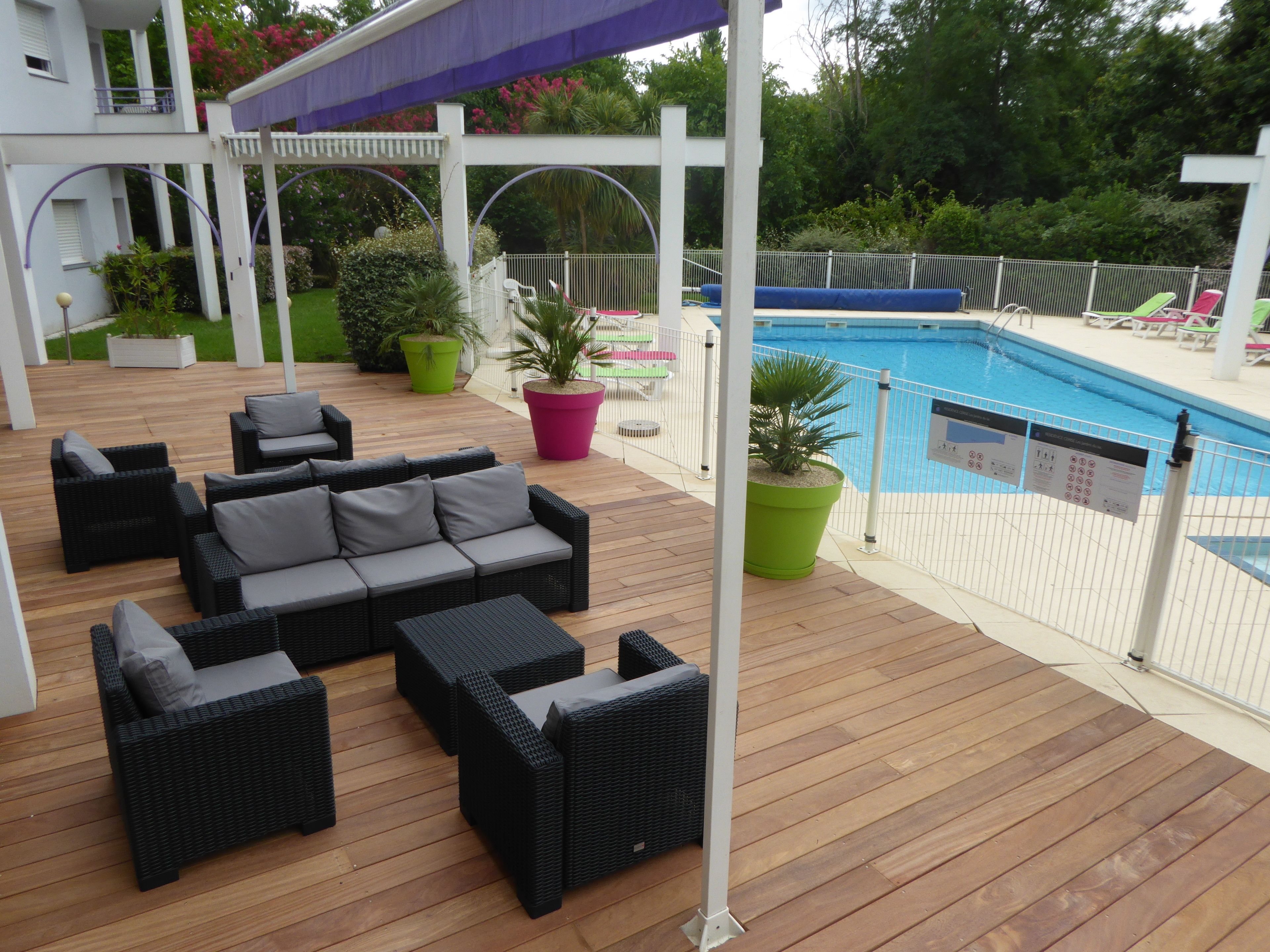 A wooden deck with outdoor furniture and a pool.