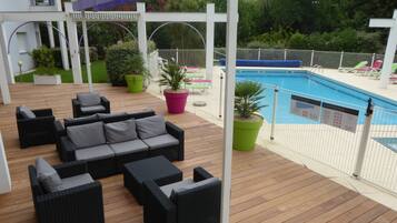 Een houten terras met buitenmeubilair en een zwembad.
