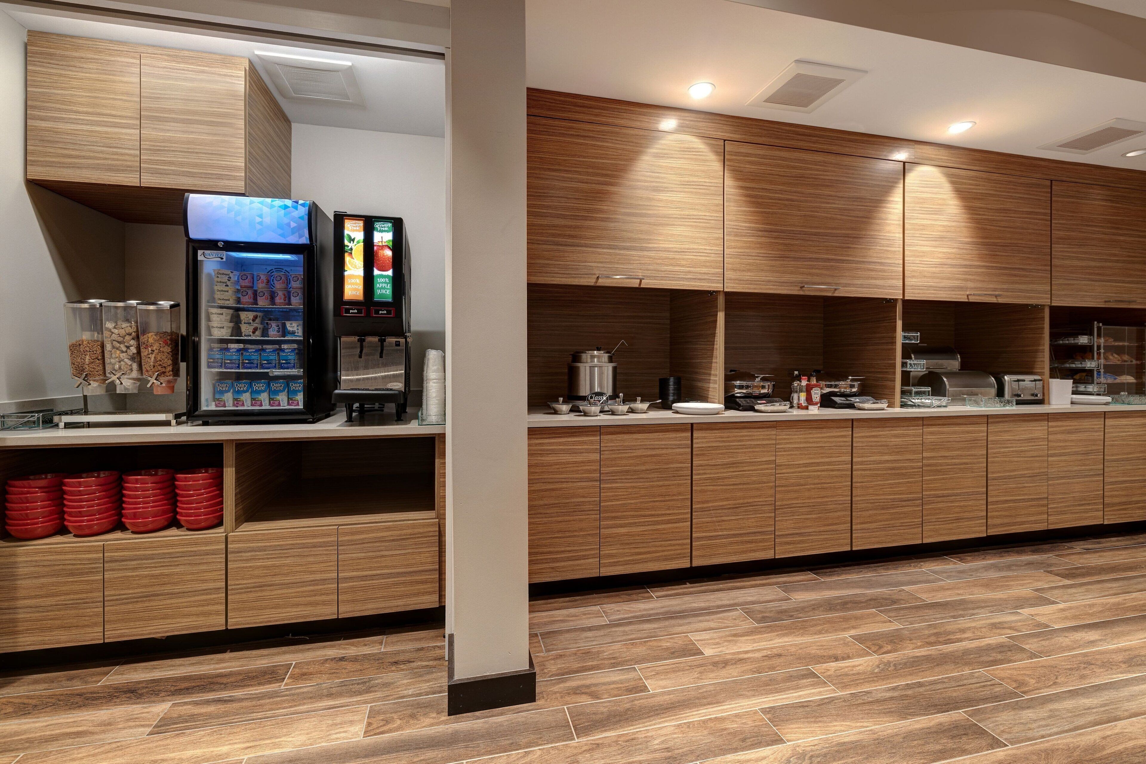 Un espace cuisine moderne avec des meubles en bois, une machine à café et un distributeur de boissons.