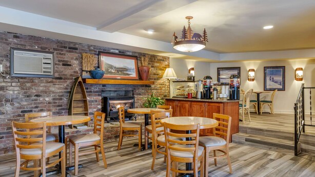A cozy dining area with wooden tables and chairs, a brick wall, and a fireplace. -  Econo Lodge Cherokee Near Island Park (Cherokee)