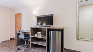 A hotel room with a wooden desk, a chair, a flat-screen TV, a mini-fridge, and a lamp. -  Econo Lodge Cherokee Near Island Park (Cherokee)