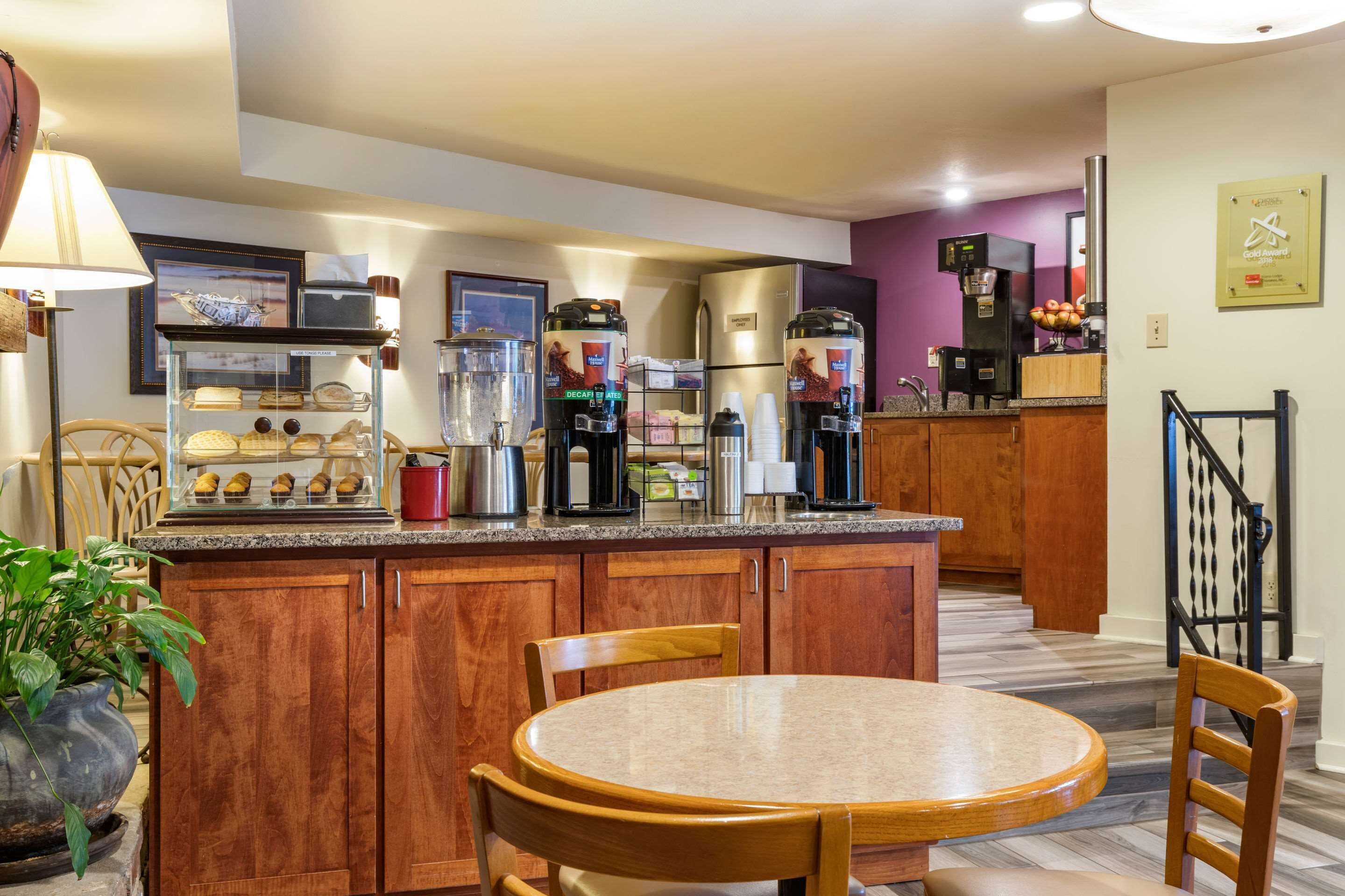 A modern kitchen with wooden cabinets, a granite countertop, a coffee station, and a dining area with a round table and chairs.
