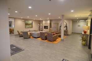 A spacious living area with a sofa set, patterned chairs, a fireplace, and a large clock on the wall.