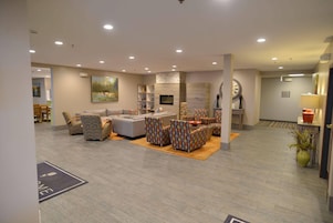 Un amplio espacio habitable con un conjunto de sofás, sillones estampados, una chimenea y un reloj grande en la pared.