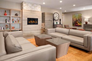 A modern living room with a fireplace, sofas, a coffee table, and a bookshelf. - Country Inn & Suites by Radisson, Duluth North, MN (Hermantown)
