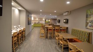 A restaurant with multiple tables and chairs, a counter with a cash register, and a television mounted on the wall. - Country Inn & Suites by Radisson, Duluth North, MN (Duluth)