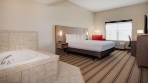 Habitación de hotel con una cama grande, baño independiente con bañera, televisor de pantalla plana y un ventanal amplio.