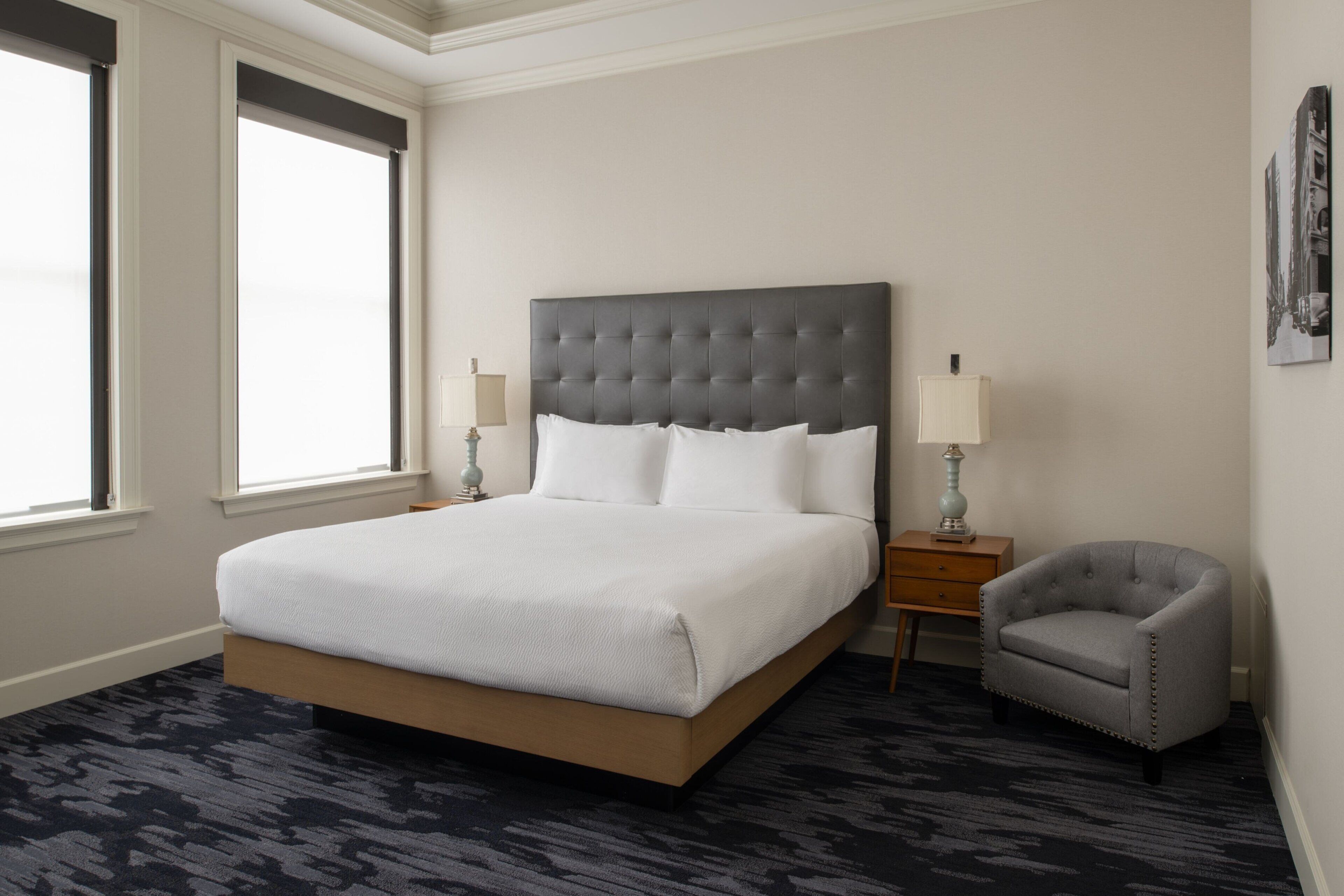 Une chambre d’hôtel avec un grand lit, deux tables de chevet, une chaise et une fenêtre.