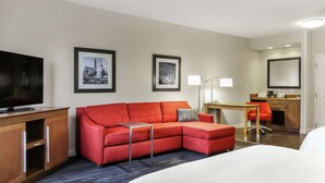 A hotel room with a bed, a red sofa, a desk with a chair, a TV, and framed pictures on the wall. - Hampton Inn Heath-Newark (Heath)