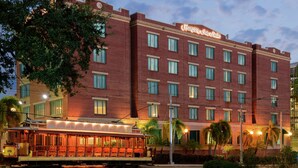 Een hotel van rode baksteen met een bord waarop staat 'Hampton Inn & Suites'.
