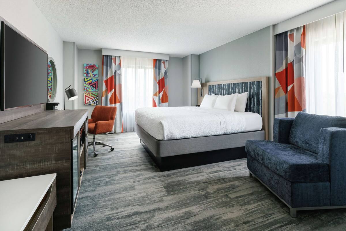 Een moderne hotelkamer met een groot bed, een bureau, een stoel en een televisie.