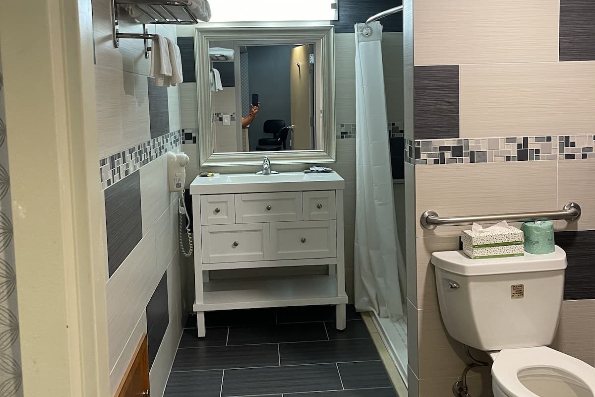 A bathroom with a white vanity, a toilet, and a shower area.