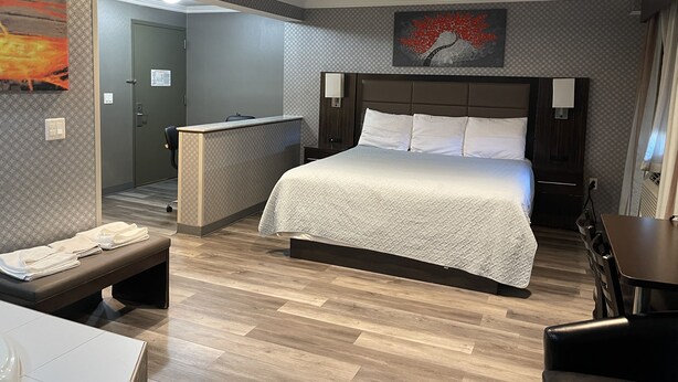 Habitación de hotel con una cama grande, un escritorio, un banco y una pequeña zona de estar.