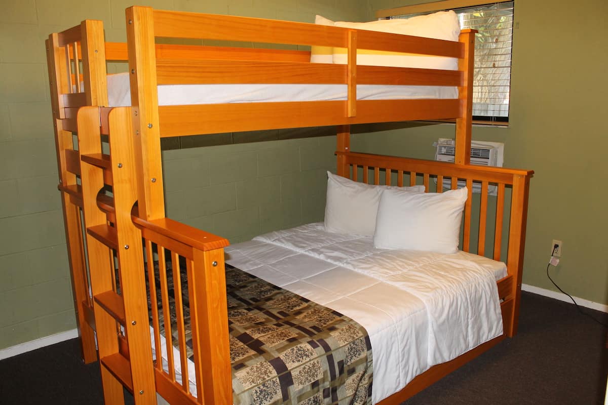 Uma cama beliche com estrutura de madeira e roupa de cama branca.
