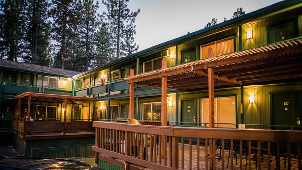 A multi-story hotel with a wooden deck and outdoor seating area.