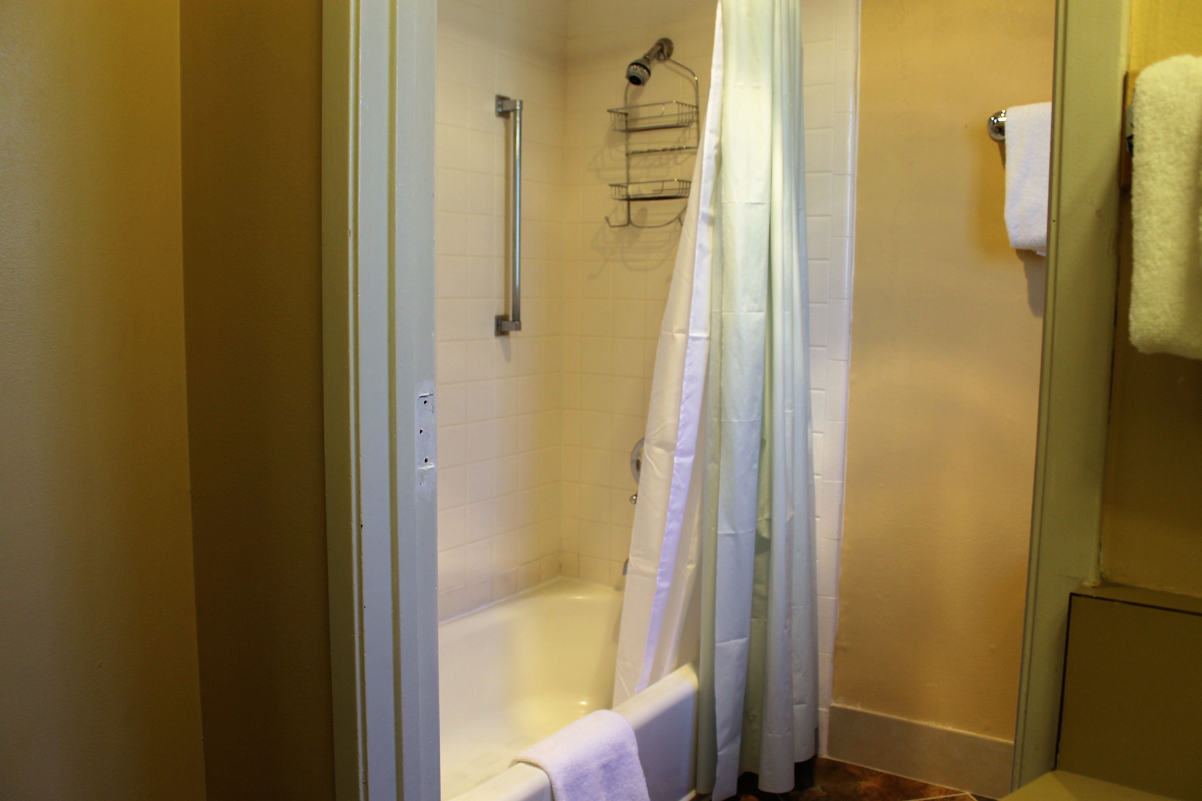 Une salle de bain équipée d’une douche, d’une baignoire, d’un porte-serviettes et de toilettes.