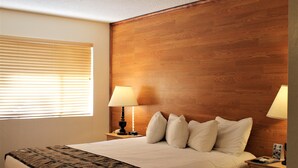 A neatly made bed with a patterned blanket, two bedside lamps, and a wooden headboard.