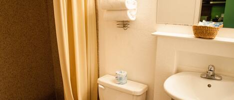 Un baño con ducha, inodoro, lavabo y un espejo con luces arriba.