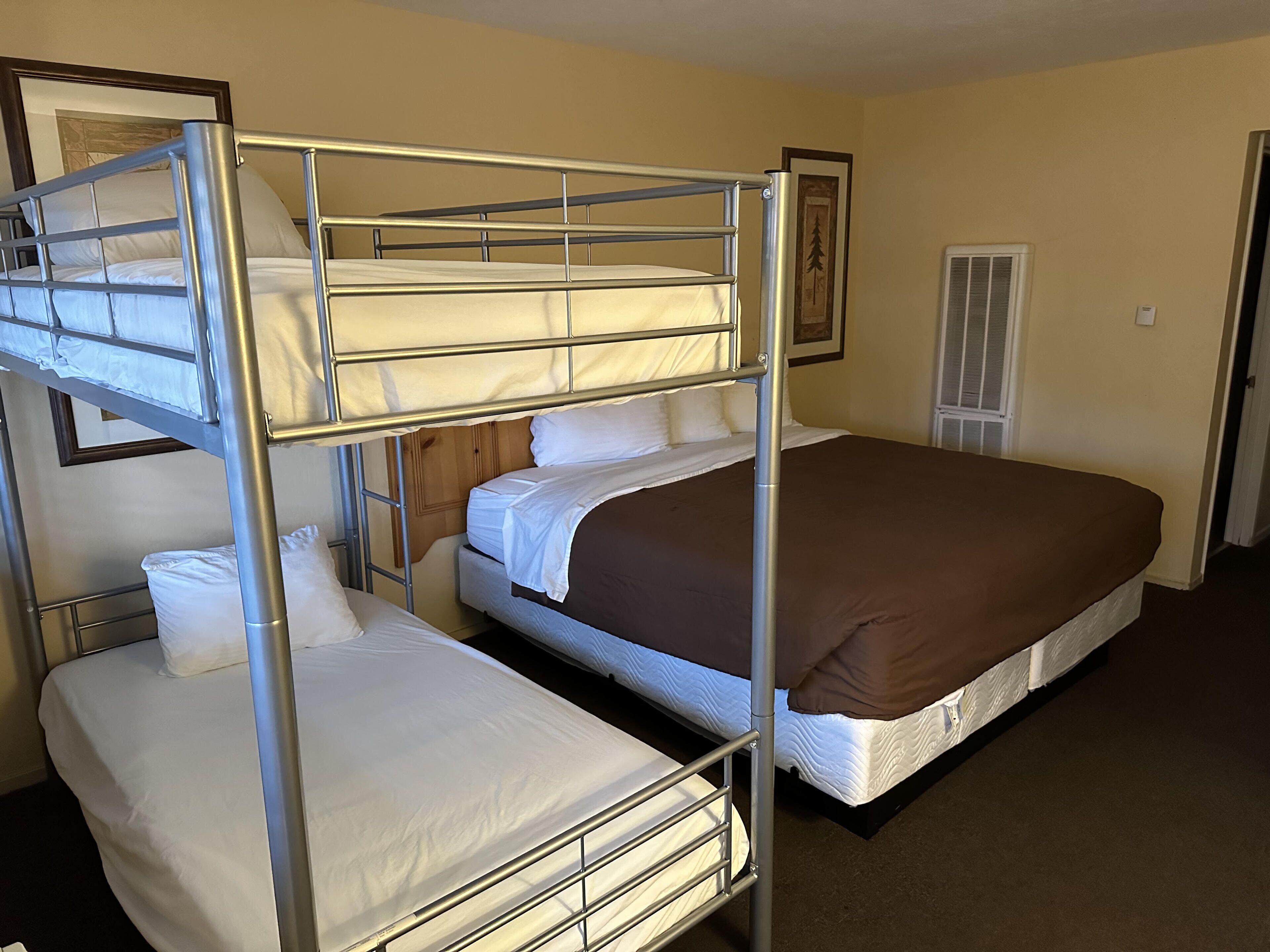 A room with two bunk beds and a single bed, all with white bedding.