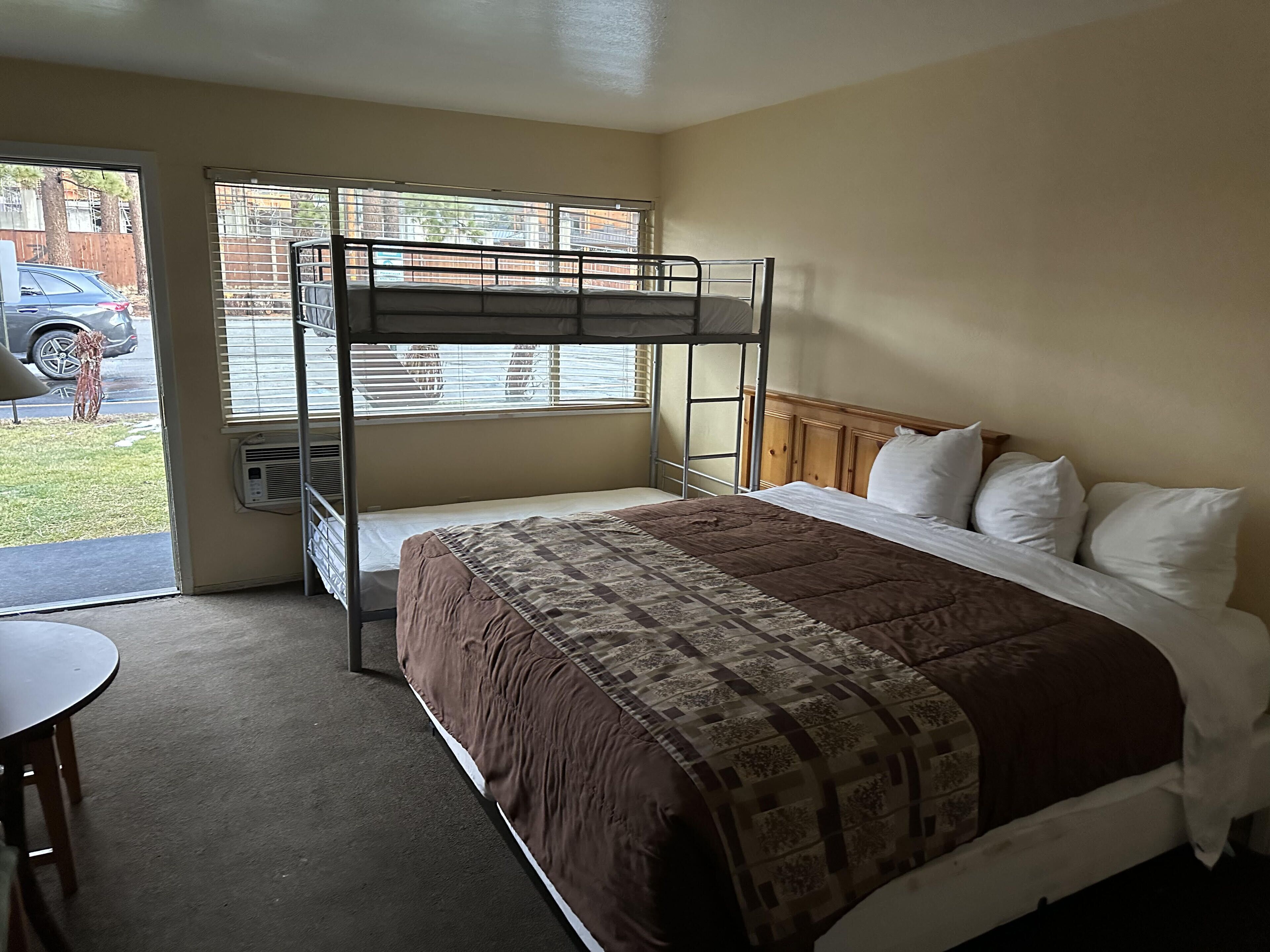 Dormitorio con literas, una ventana, una mesa y una puerta que da al exterior.