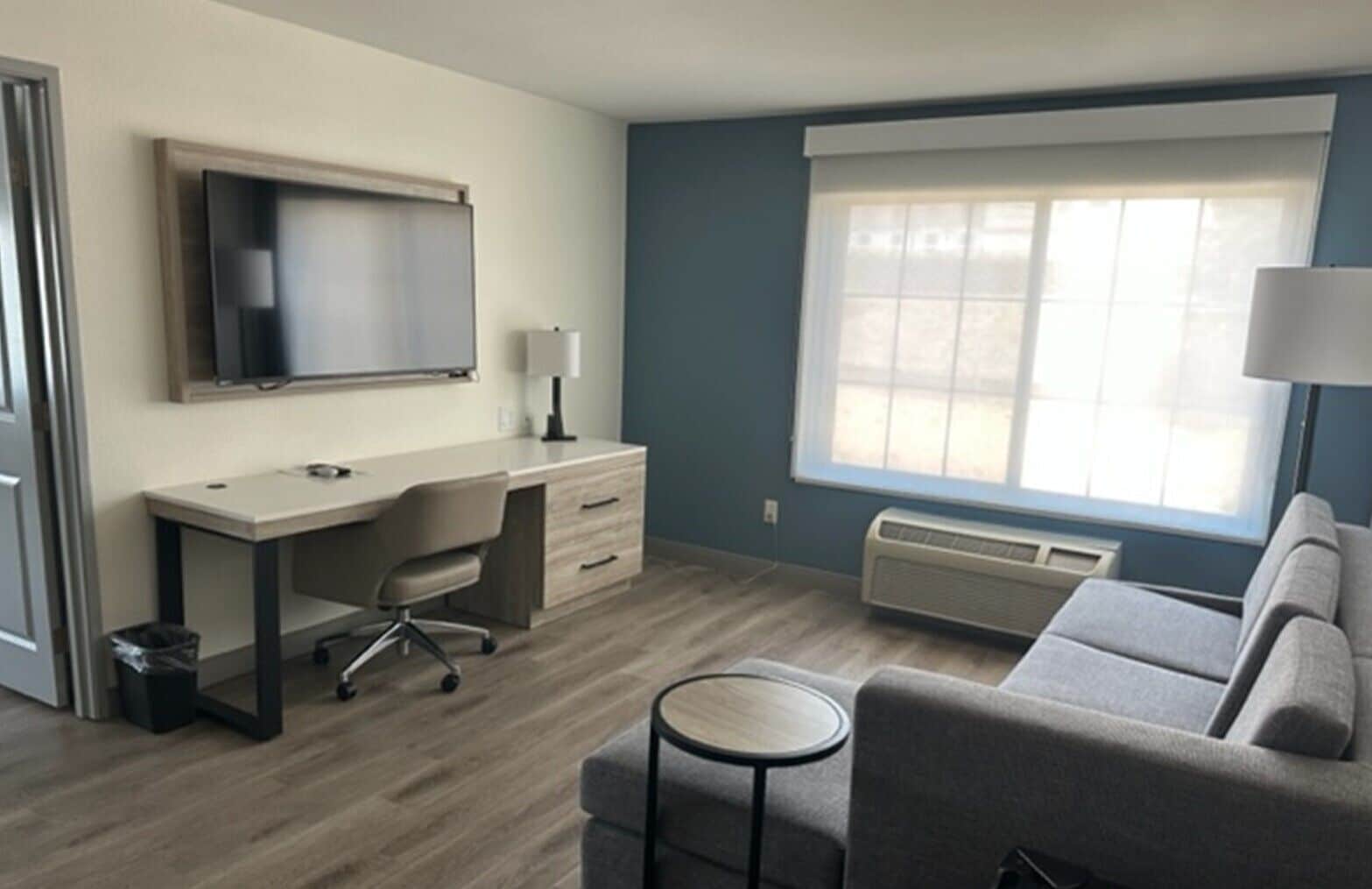 A modern hotel room with a desk, chair, and sofa.