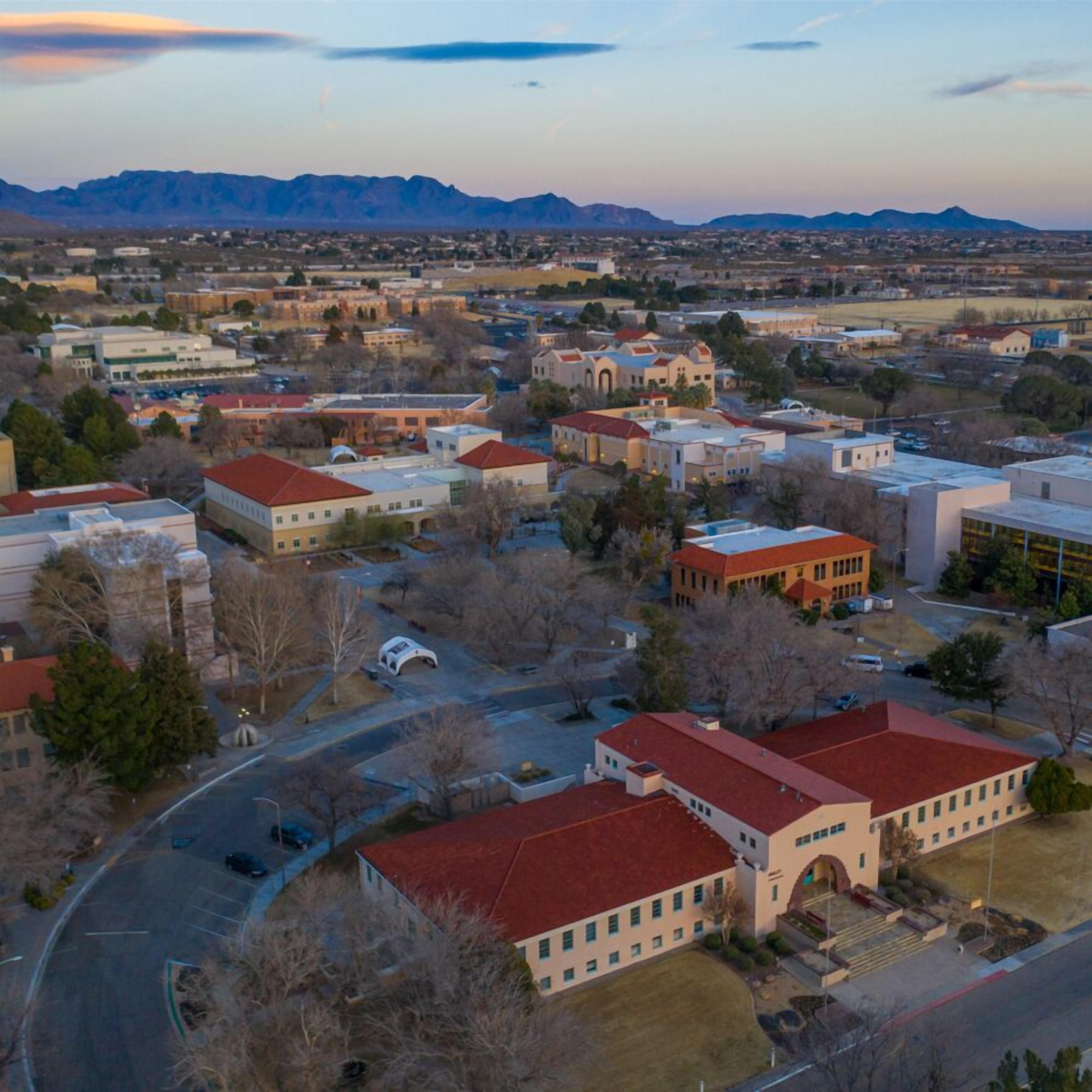 An aerial view of a campus with multiple buildings, roads, and surrounding mountains.