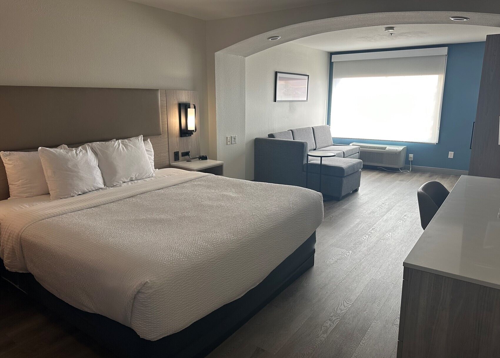 Ein modernes Hotelzimmer mit einem großen Bett, einem Schreibtisch, einem Sessel und einer Couch.