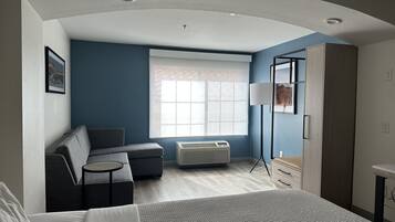 A modern hotel room with a bed, a sofa, a desk, and a wardrobe.