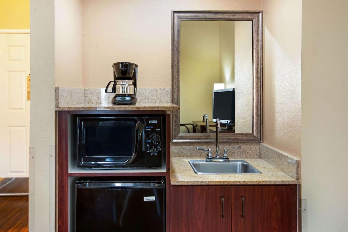 A compact kitchenette with a microwave, coffee maker, and a sink.