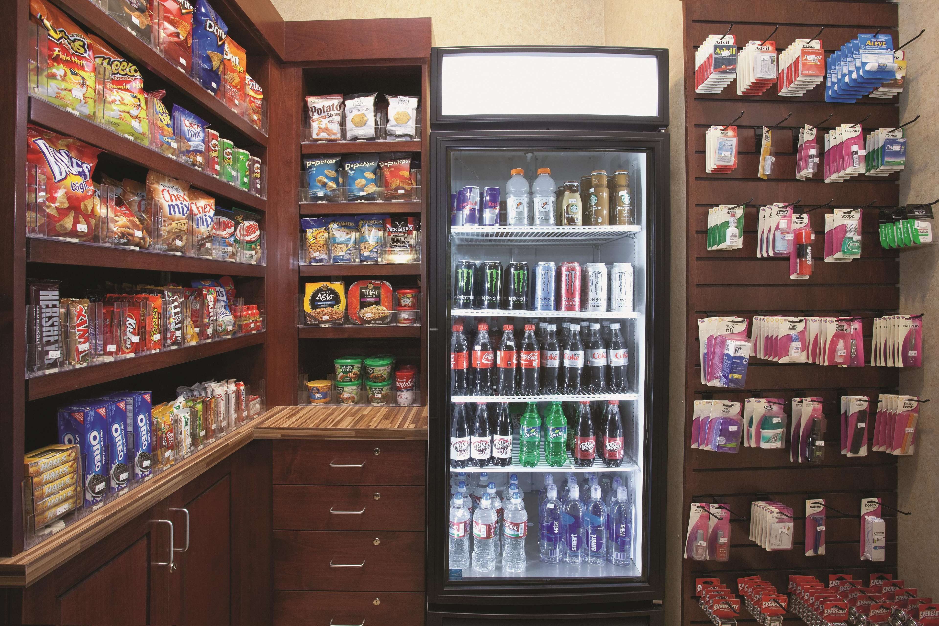 Una tienda de comestibles con estantes llenos de productos de snacks, bebidas y artículos del hogar.