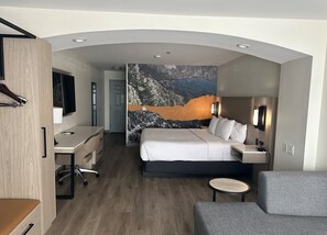 Una habitación de hotel moderna con una cama grande, un escritorio, una silla y una mesita.
