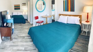 Habitación de hotel con dos camas, un escritorio, una silla y una mesita.