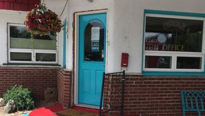 Un edificio con puerta azul, un cesto de flores colgante y un escalón pintado de rojo y azul que lleva a la entrada.