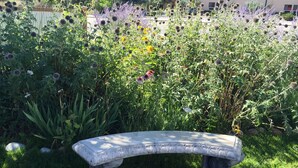 Un banco de piedra en un jardín con diversas plantas y flores.