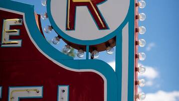 Un letrero de neón con la letra 'R' y un diseño circular, parte de una estructura más grande con una combinación de colores rojo y azul.
