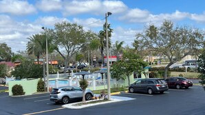 A parking lot with several cars, a playground with a slide, and a building with a green roof. - Gulf Way Inn (Clearwater)