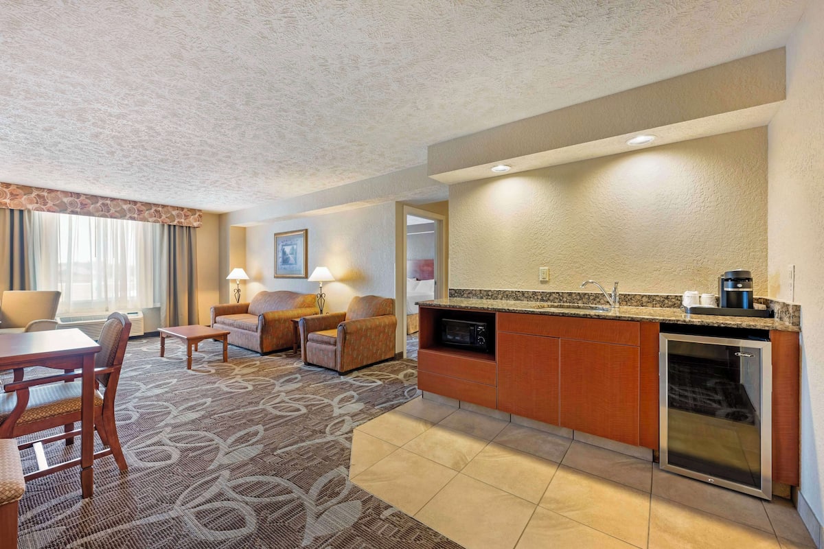 A hotel room with a dining area, a sofa, a coffee machine, and a microwave.