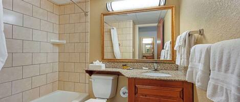A bathroom with a bathtub, toilet, sink, and a mirror.