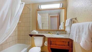 A bathroom with a bathtub, toilet, sink, and a mirror above the sink.
